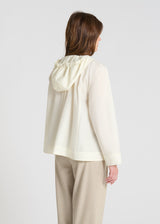 Détail veste femme blanc cassé, capuche avec liens gros grain logo, poches plaquées boutons nacre, blouson léger