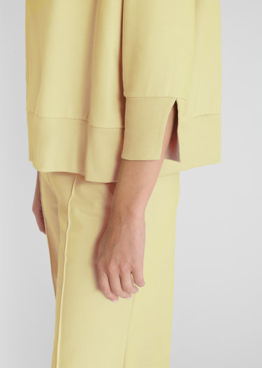 Détail sweat jaune femme, découpes graphiques au dos, fentes au bas - Vue arrière rapprochée Balisier
