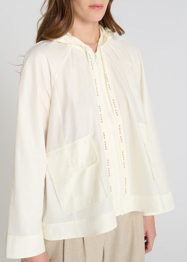 Veste légère femme blanc cassé, tissu technique, blouson capuche urbain coupe fluide pour vestiaire moderne
