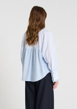 Détail chemisier femme bleu ciel rayé, manches longues bouffantes, larges poignets boutonnés, blouse chic coton
